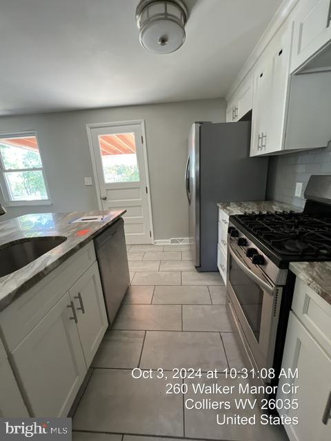 kitchen with a wealth of natural light, white cabinetry, and appliances with stainless steel finishes