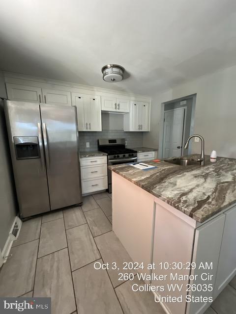 kitchen featuring white cabinets, sink, stainless steel appliances, dark stone countertops, and decorative backsplash