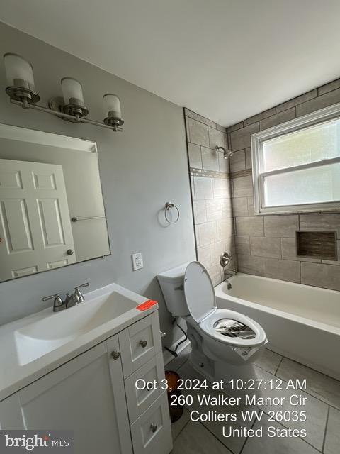 full bathroom with tile patterned flooring, tiled shower / bath, vanity, and toilet