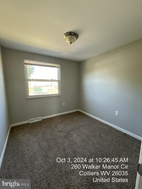 spare room featuring dark colored carpet