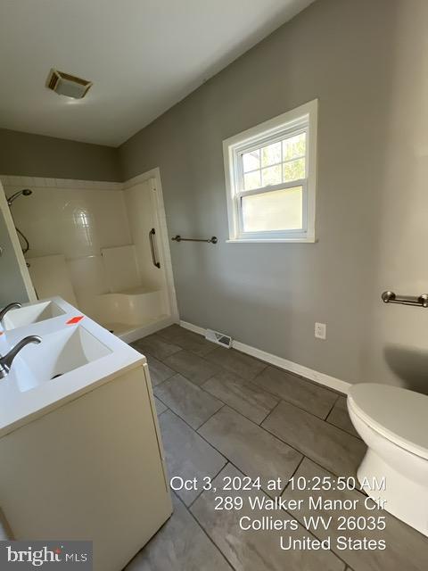 bathroom featuring tile patterned floors, walk in shower, vanity, and toilet