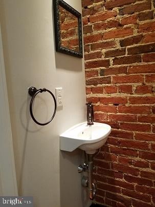 bathroom featuring brick wall and sink