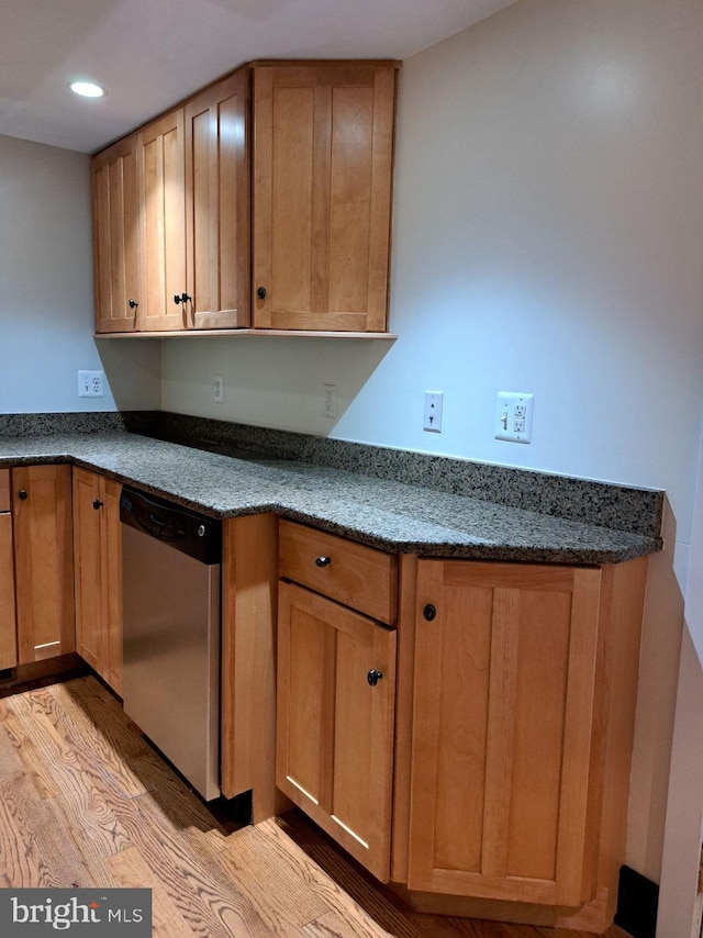 kitchen with dishwasher, light wood-type flooring, and dark stone counters