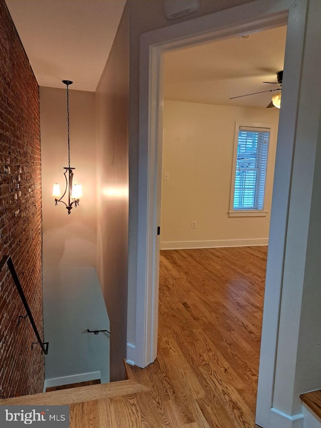 hall featuring wood-type flooring and brick wall