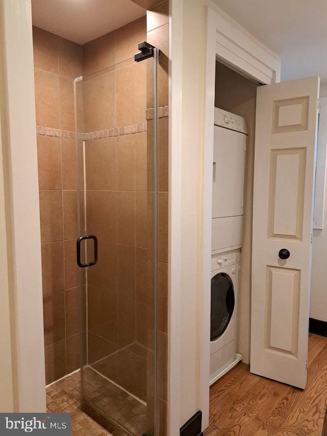 bathroom featuring stacked washer / dryer, walk in shower, and hardwood / wood-style floors