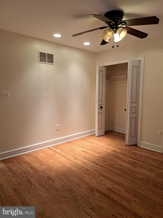 unfurnished bedroom with ceiling fan, a closet, and hardwood / wood-style flooring