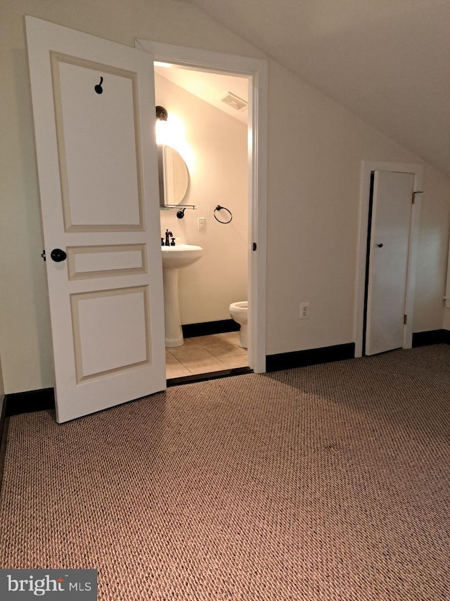 interior space with light carpet, connected bathroom, and lofted ceiling