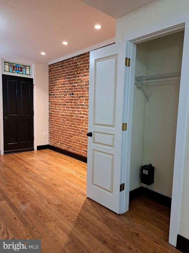 interior space with brick wall, hardwood / wood-style flooring, and a closet