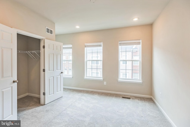 unfurnished bedroom with light colored carpet and a closet