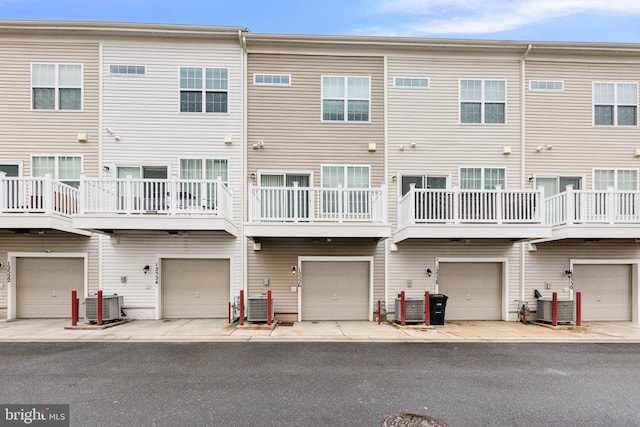 back of property featuring a balcony, a garage, and central air condition unit