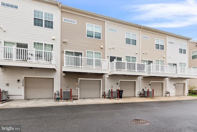 back of property with a balcony, central AC, and a garage