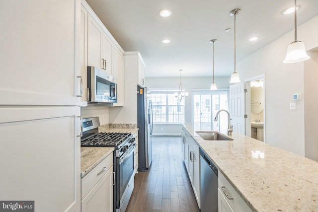 kitchen featuring hanging light fixtures, sink, dark wood-type flooring, white cabinetry, and stainless steel appliances