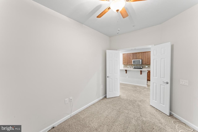 carpeted spare room with ceiling fan