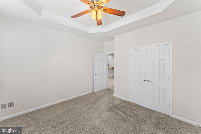 unfurnished bedroom featuring carpet, a tray ceiling, and ceiling fan