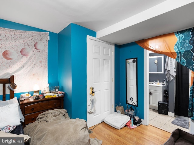 bedroom featuring sink, light hardwood / wood-style flooring, and ensuite bath