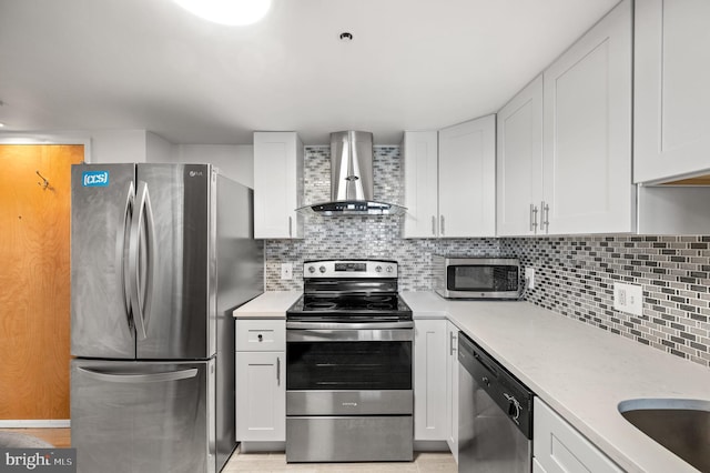 kitchen featuring appliances with stainless steel finishes, decorative backsplash, white cabinets, light stone countertops, and wall chimney range hood