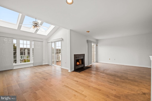 unfurnished living room featuring light hardwood / wood-style floors, ceiling fan, a skylight, and high vaulted ceiling