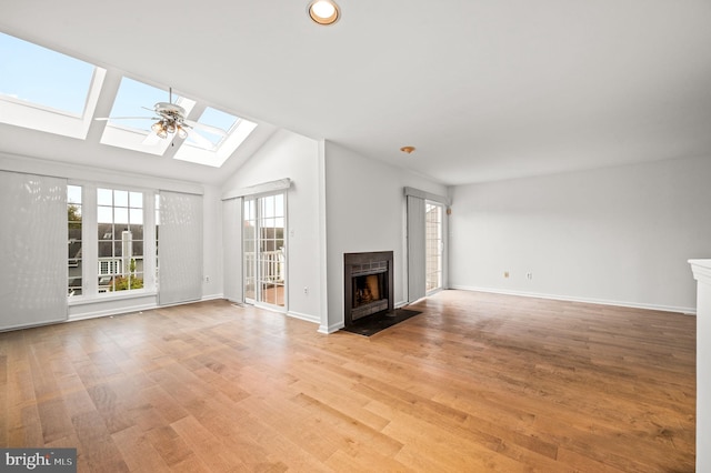 unfurnished living room with ceiling fan, a skylight, light hardwood / wood-style floors, and high vaulted ceiling