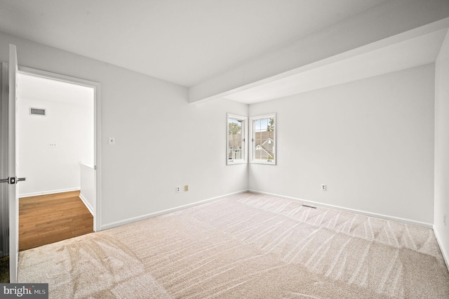 empty room featuring wood-type flooring and beamed ceiling