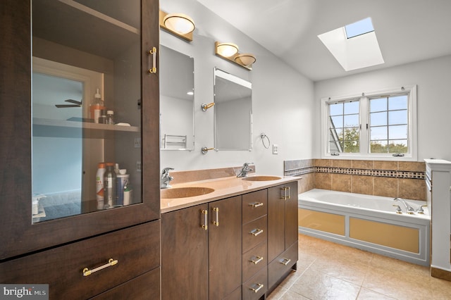 bathroom with a skylight, vanity, a bath, and tile patterned floors