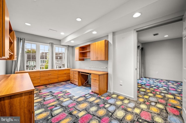 kitchen with carpet, built in desk, and dishwasher