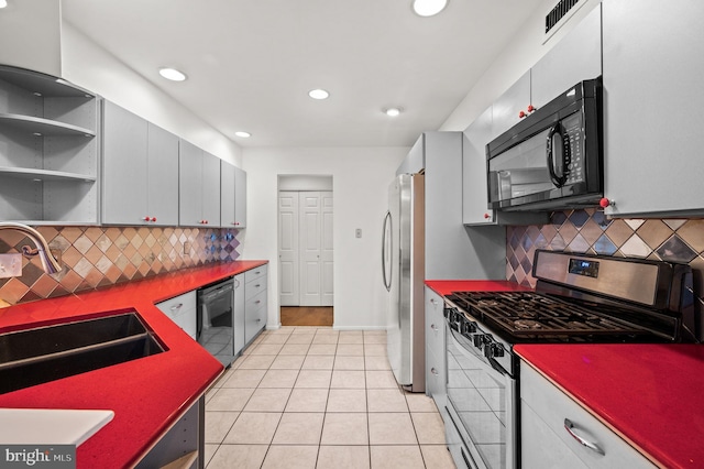 kitchen featuring backsplash, black appliances, light tile patterned floors, and sink