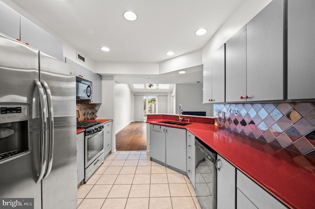 kitchen with black appliances, light tile patterned flooring, decorative backsplash, and sink