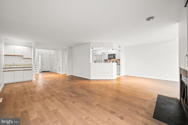 unfurnished living room featuring light hardwood / wood-style floors and sink