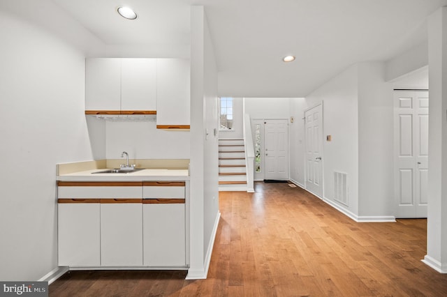 interior space featuring white cabinets, sink, and light hardwood / wood-style floors