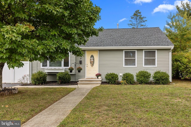 view of front of property featuring a shingled roof, fence, and a front lawn