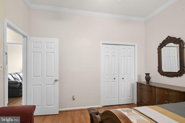 bedroom with a closet, light hardwood / wood-style flooring, and ornamental molding