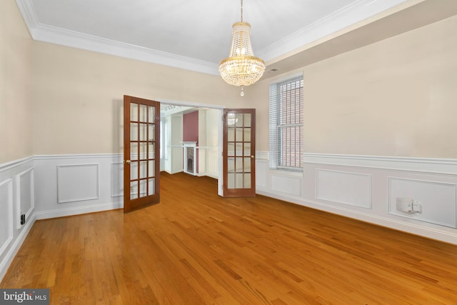 unfurnished room featuring french doors, crown molding, a notable chandelier, and hardwood / wood-style floors