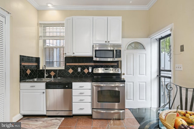 kitchen with sink, tile patterned floors, crown molding, white cabinets, and appliances with stainless steel finishes