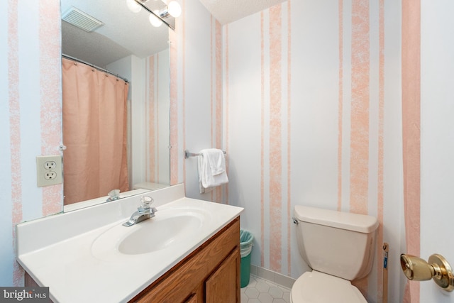 bathroom featuring a textured ceiling, vanity, and toilet