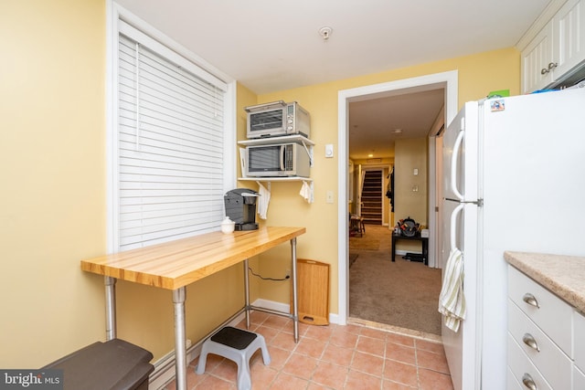 kitchen featuring white cabinetry, white refrigerator, light colored carpet, and wooden counters