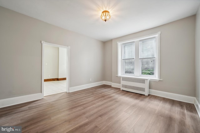 unfurnished room with hardwood / wood-style floors and radiator