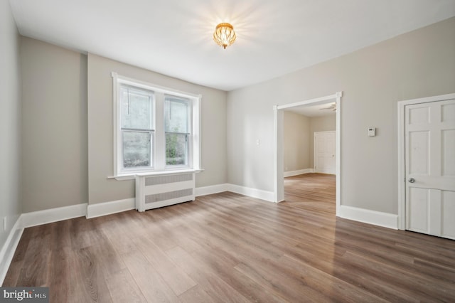 unfurnished room featuring radiator and wood-type flooring