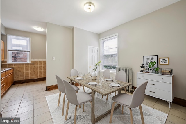 tiled dining room featuring radiator, tile walls, and a healthy amount of sunlight