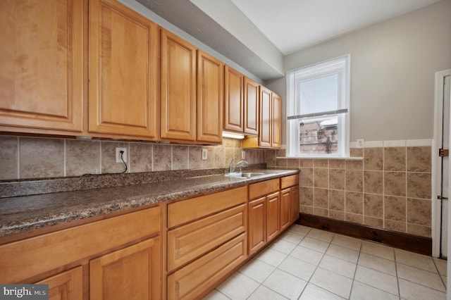 kitchen with sink, dark stone countertops, and light tile patterned floors