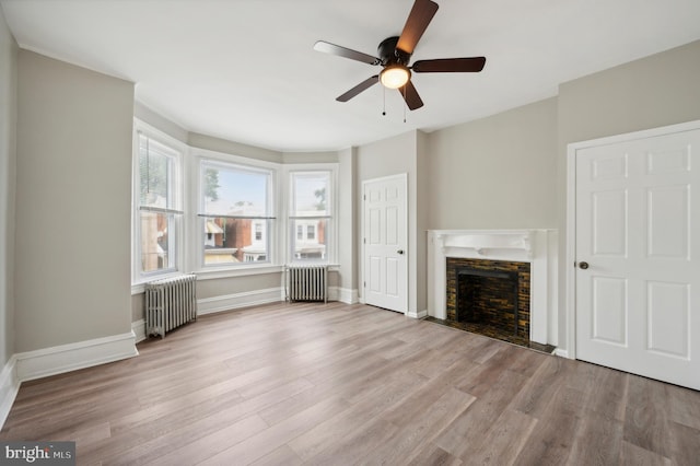 unfurnished living room featuring light hardwood / wood-style floors, ceiling fan, and radiator