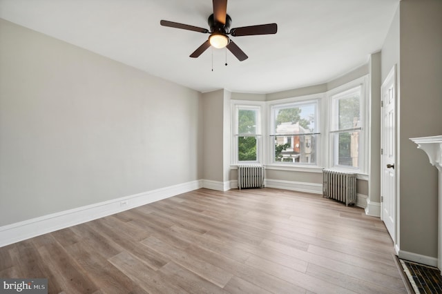 unfurnished room with radiator, ceiling fan, and light wood-type flooring