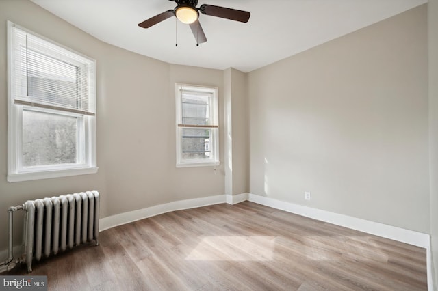 unfurnished room featuring radiator, ceiling fan, and light hardwood / wood-style floors