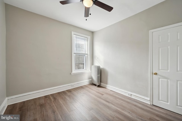 spare room featuring radiator, light wood-type flooring, and ceiling fan