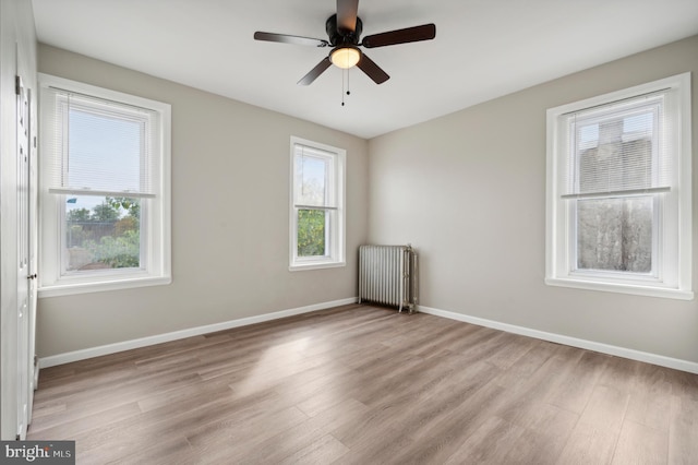 spare room featuring radiator, ceiling fan, and light wood-type flooring