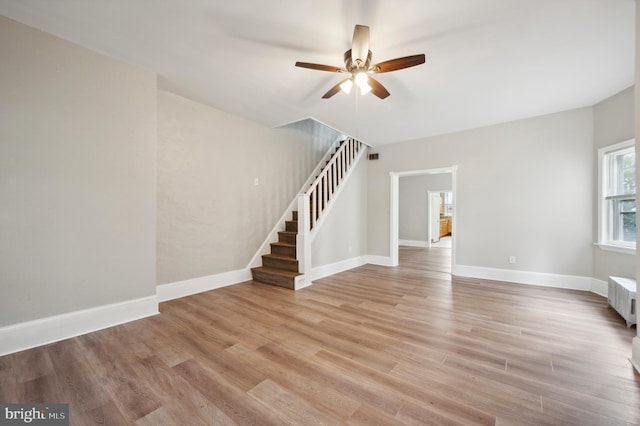 unfurnished living room with light wood-type flooring, radiator heating unit, and ceiling fan