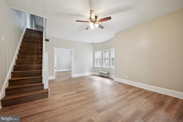 unfurnished living room with light wood-type flooring, radiator heating unit, and ceiling fan