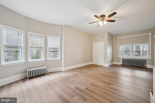 empty room featuring radiator heating unit, a healthy amount of sunlight, and light hardwood / wood-style flooring