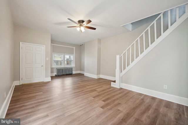 unfurnished living room with hardwood / wood-style floors, ceiling fan, and radiator heating unit