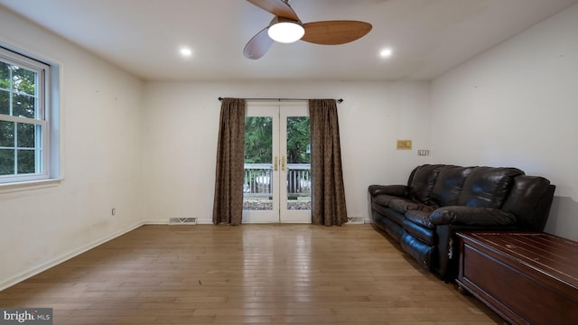 living room featuring light wood-type flooring, ceiling fan, and french doors