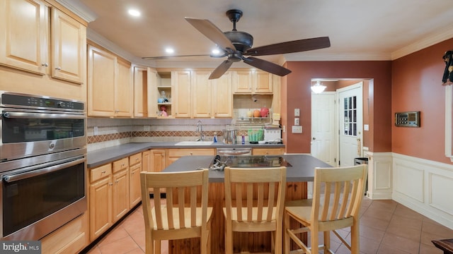 kitchen with decorative backsplash, a breakfast bar area, stainless steel appliances, crown molding, and light brown cabinetry